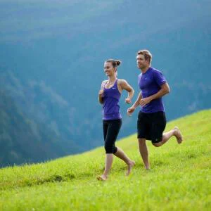 Ein Mann und eine Frau beim Laufen auf dem grünen Feld in den Bergen