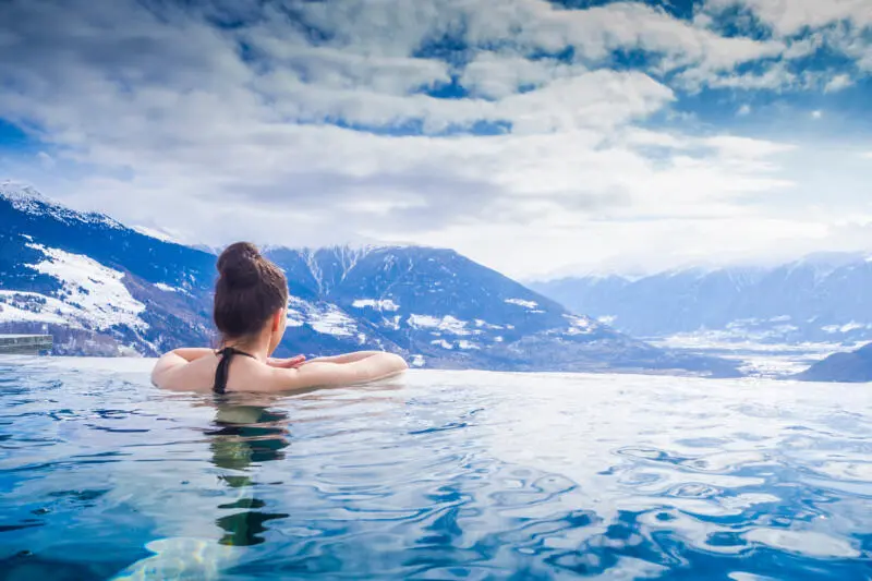 Frau geniesst Bergpanorama im Winter vom Pool aus